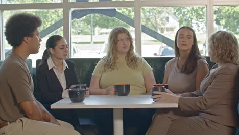 office meeting close up with one senior citizen woman and four younger workers with video pull out slowly