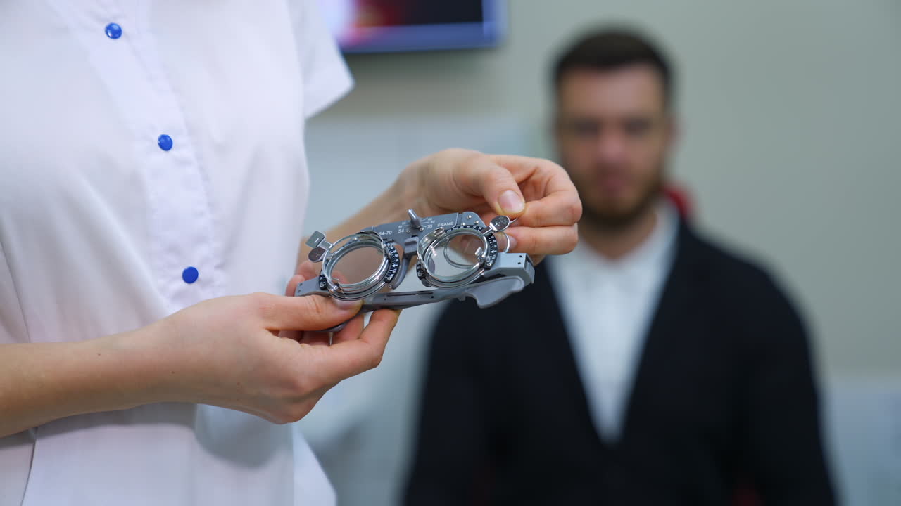 Ophthalmological trial frame and test glasses in woman's hands. Eysight correction. Young man on blurred background.