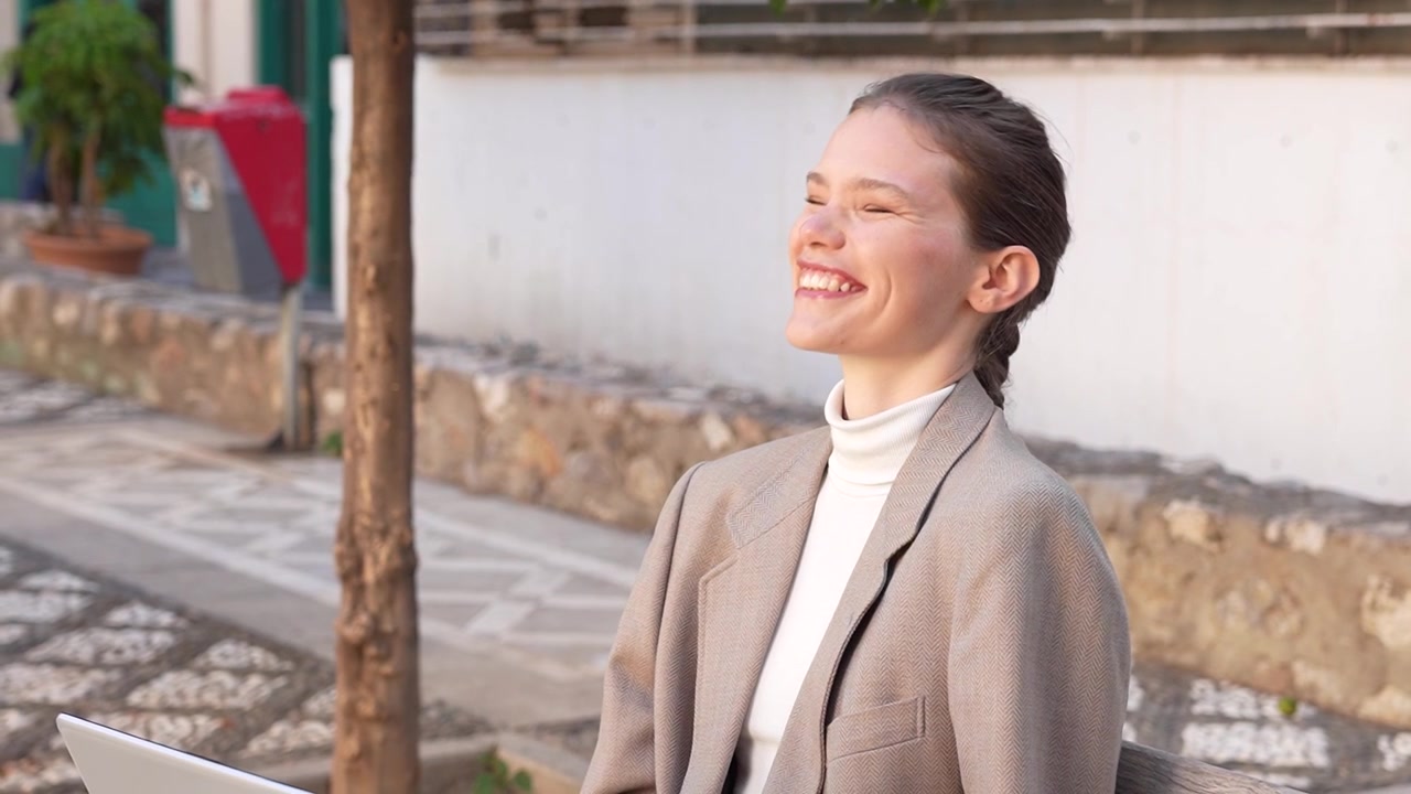 生産性向上のためノートパソコンを使いながら、屋外で仕事に取り組むプロフェッショナルな女性。