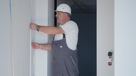 un electricista con casco instala y comprueba las tiras de led para la iluminación en el apartamento. compruebe la luz y la iluminación decorativa