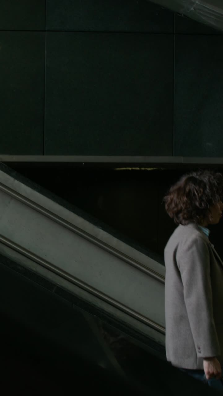 mujer subiendo una escalera mecánica en un edificio moderno