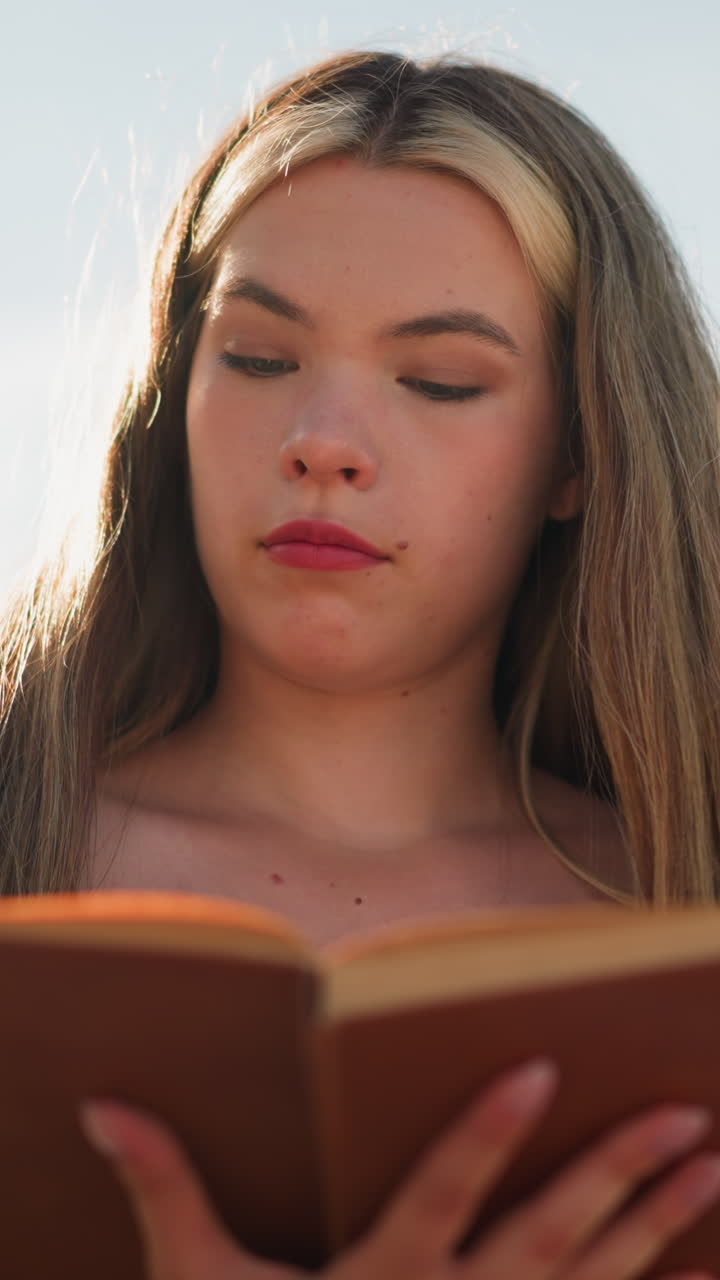 cerca de una joven pensativa de negro revisa un libro bajo un cielo brillante, encuentra un pedazo de papel entre las páginas y lo mira contemplativamente, mientras la luz del sol ilumina suavemente su rostro