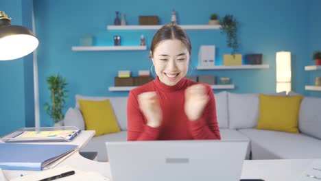 beautiful asian woman screaming with joy while browsing laptop, happy at what she sees on screen.