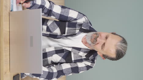 Vertical-video-of-Old-man-working-on-laptop-with-happy-expression.