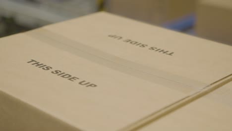 primer plano de una caja de cartón con la etiqueta "este lado hacia arriba", lista para el envío