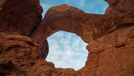 time lapse, clouds moving above natural arch and red sandstone rock formations