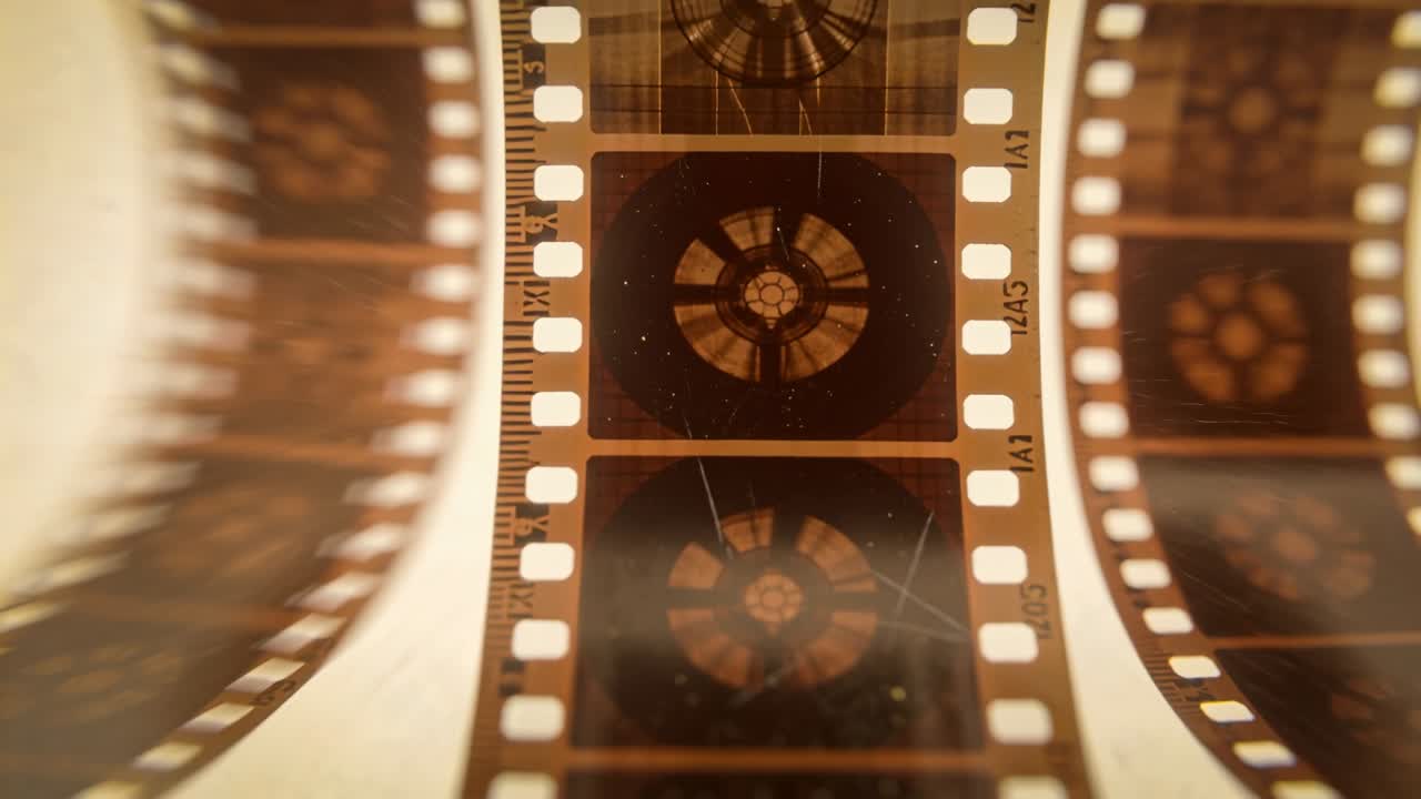 Striscia di pellicola verticale da 35mm che scorre su un tavolo luminoso dopo lo spostamento, rivelando fotogrammi del rotore e fori di trascinamento.