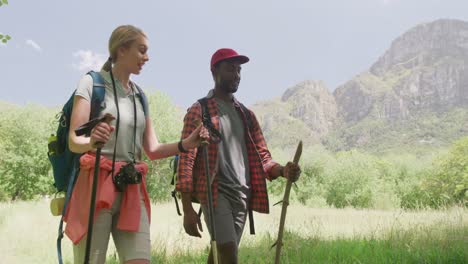 happy diverse couple hiking with backpacks in park, slow motion