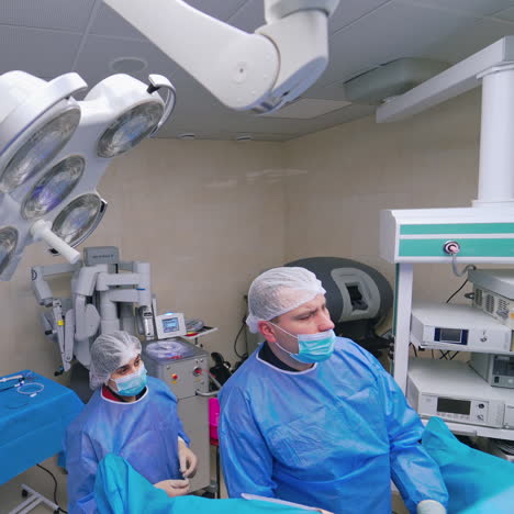 contemporary operating room. male surgeon and his assistant in medical clothing perform a surgery to a patient in clinic. healthcare concept.