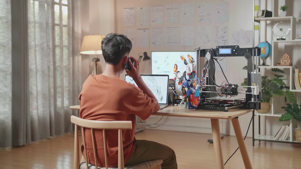집에 있는 노트북에서 사이보그 손을 디자인하는 동안 스마트폰에서 이야기하는 3d 프린팅 소년의 뒷면