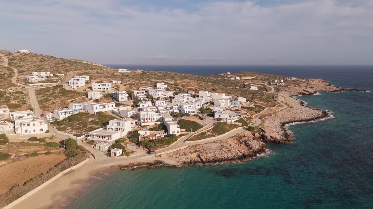 panorámica aérea que establece la vista de las casas blancas en la ladera de donousa, grecia, mientras el coche se dirige a las villas