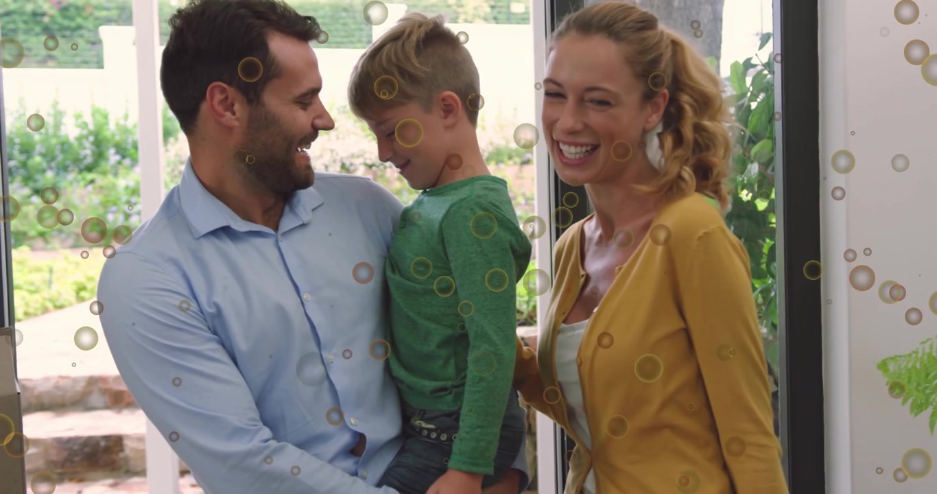 Porta che si apre, famiglia che arriva, uomo che solleva il bambino, donna che appoggia la mano, che si scambiano un caloroso saluto