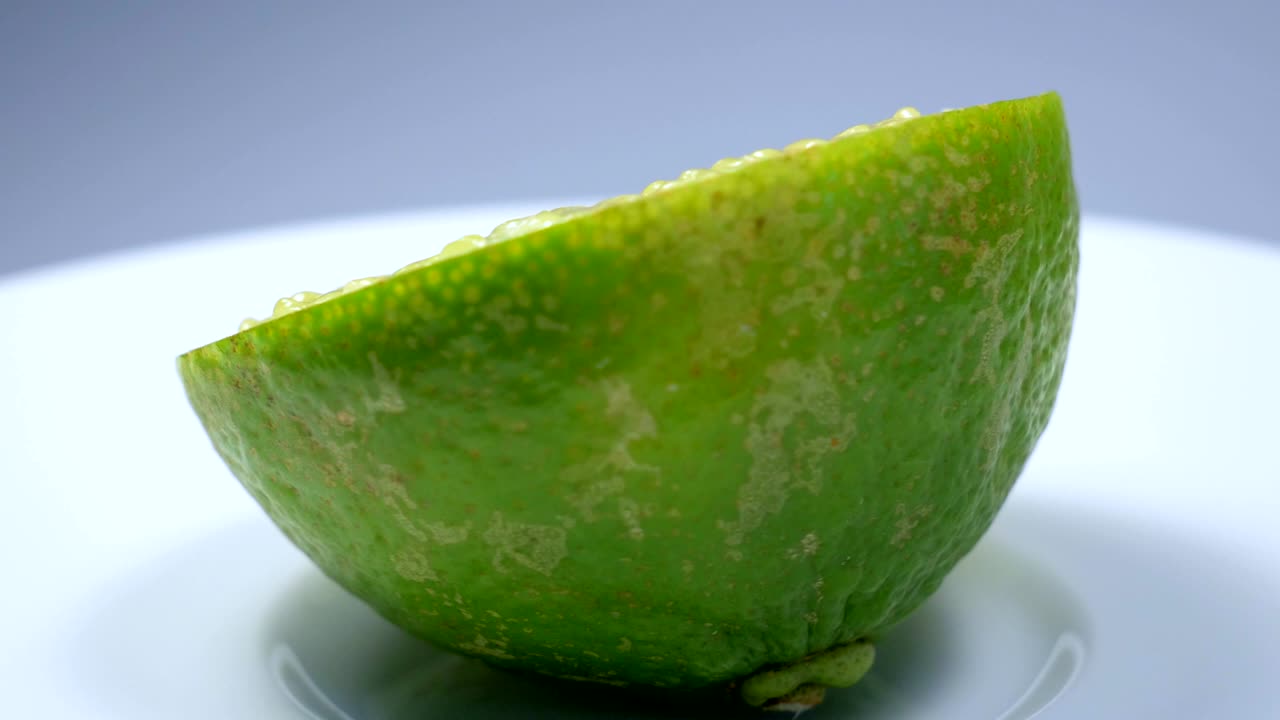 신선한 녹색 레몬 슬라이스는 세부 사항과 함께 스튜디오에서 천천히 회전하고 있습니다.
