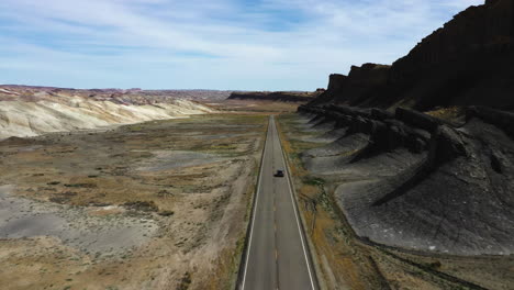 Aerial-view-following-a-car-driving-on-a-scenic-road,-sunny-day-in-southwest-USA