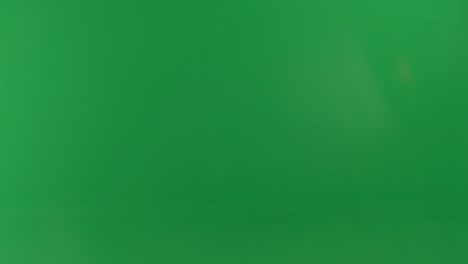 person with a large orange backpack in front of a green screen