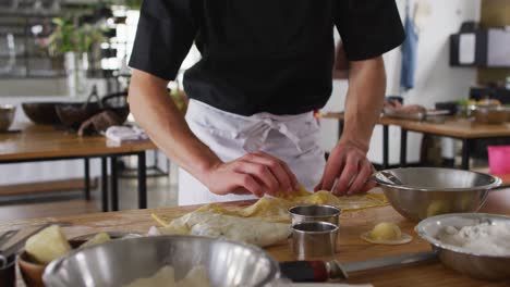 grupo diverso de chefs preparando platos y sonriendo en una cocina