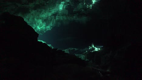 scuba divers in cave system cenote tajma ha in yucatan mexico and reflection on water surfacce