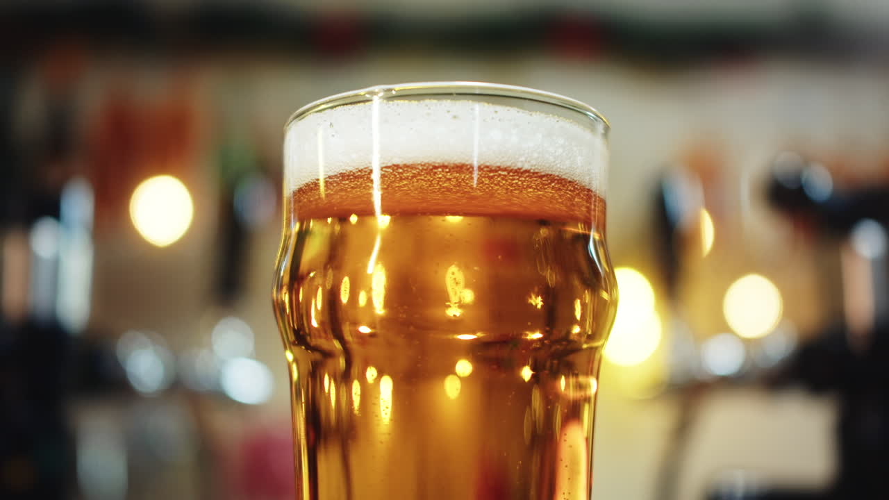 Primo piano di un bicchiere di birra dorata con schiuma in un bar