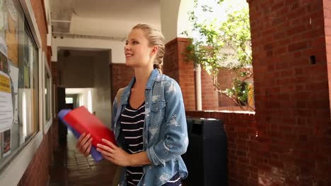 estudiante rubia comprobando el tablero de anuncios