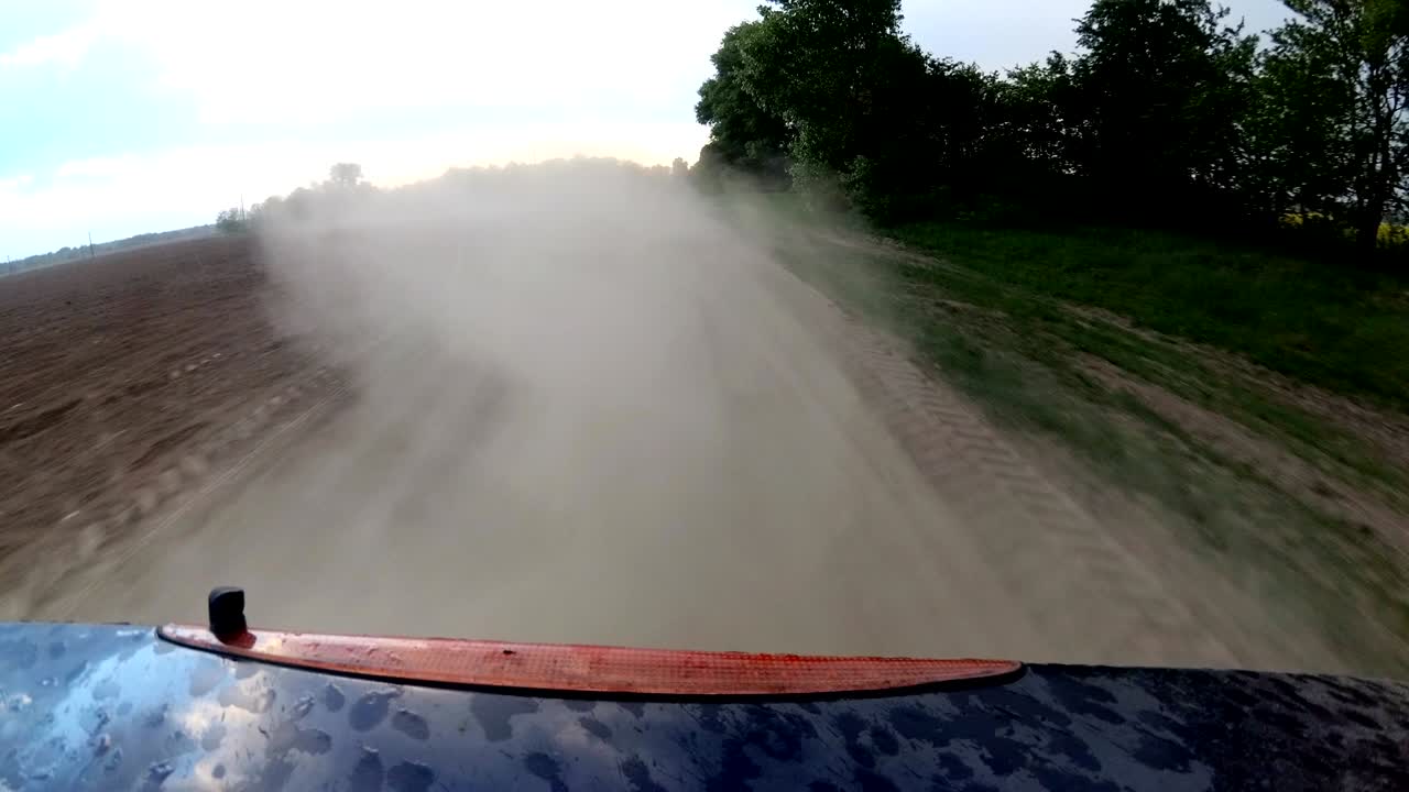 자동차 바에서 먼지가 어나오고 자동차가 시골의 자갈 도로에서 운전합니다.