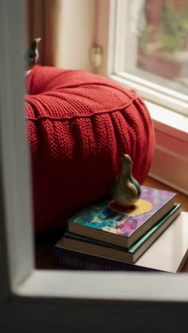 cozy home decor with red knitted pouf, books, and bird figurines