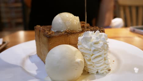 drizzling some honey over a decadent bread toast, topped with vanilla ice cream, nuts, caramel sauce, and whipped cream on the side