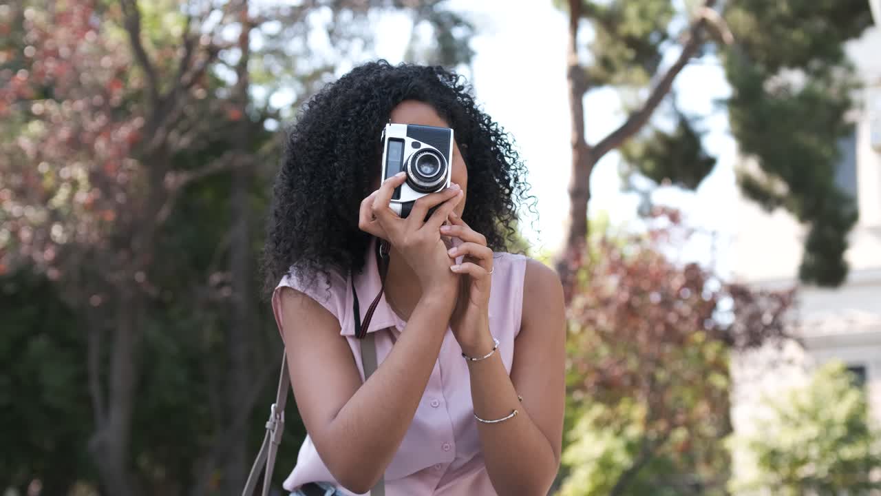 Woman using digital camera while photographing in city park during daytime