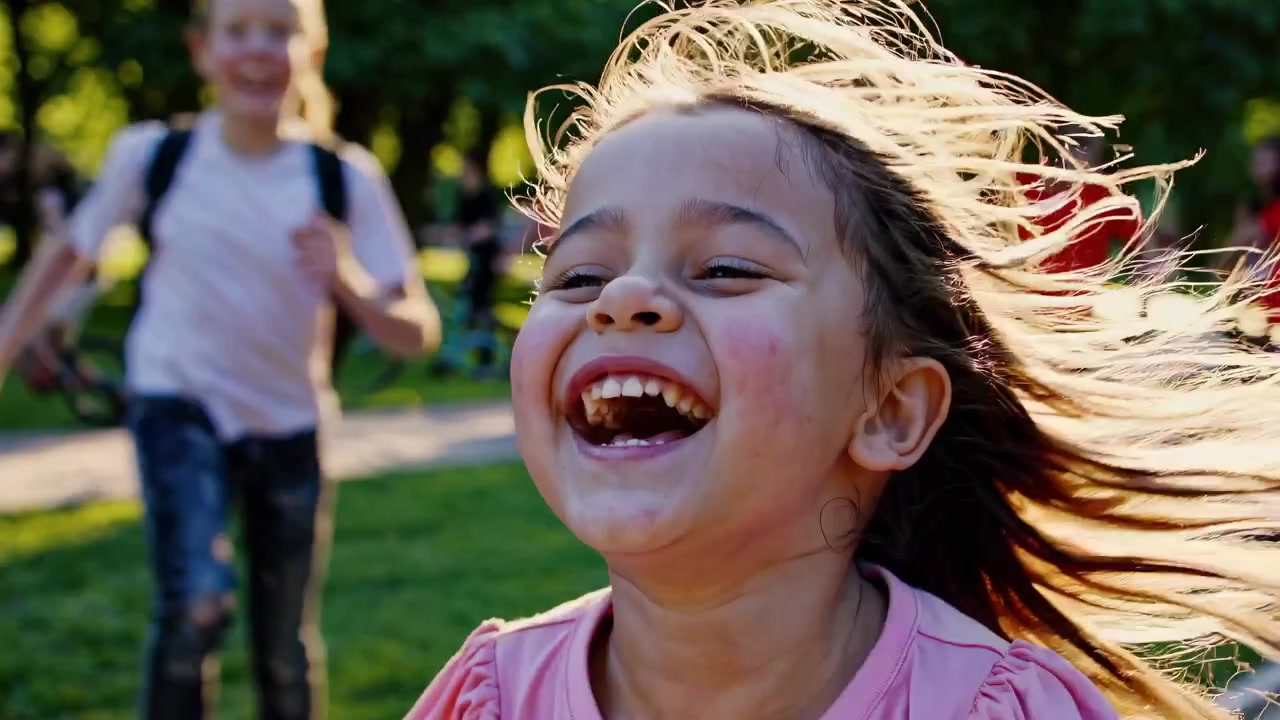Menina Alegre Rindo com os Cabelos ao Vento em um Parque Ensolarado