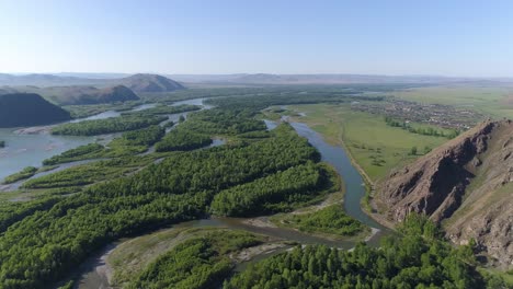 aerial view of a river winding through mountains and green fields