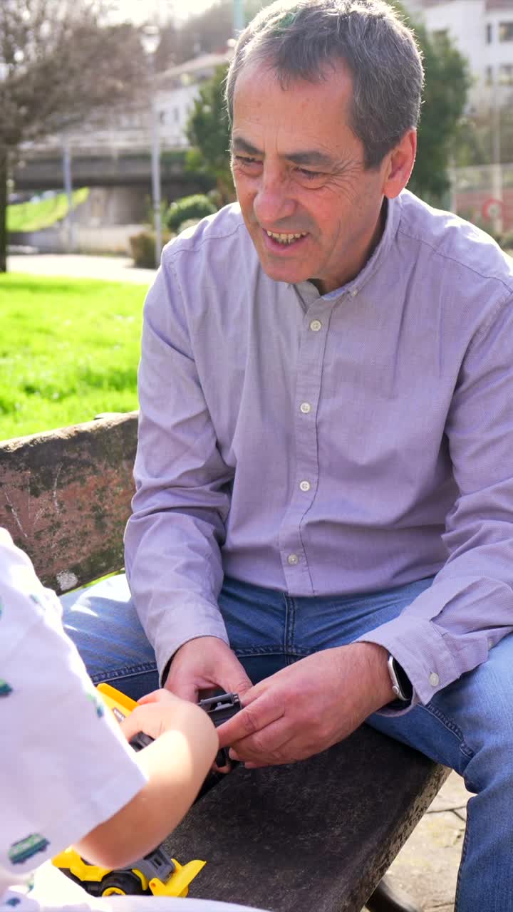 Grandfather and Grandson Playing with a Toy Car in the Park