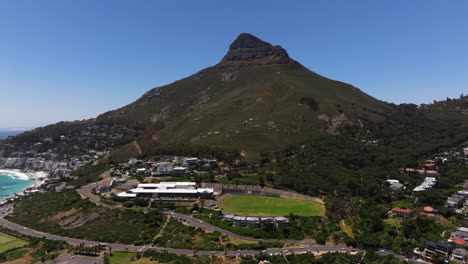 el retroceso aéreo revela la playa de camps bay con la montaña lion's head en el fondo.