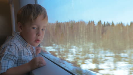 boy looking out the window of moving train