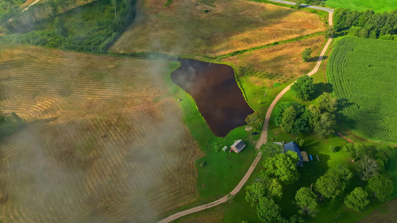 paisaje aéreo por encima de las nubes de campos de cultivos verdes y amarillos rurales y casas pequeñas drone volar en el campo ubicación, vegetación y pequeño pueblo lago