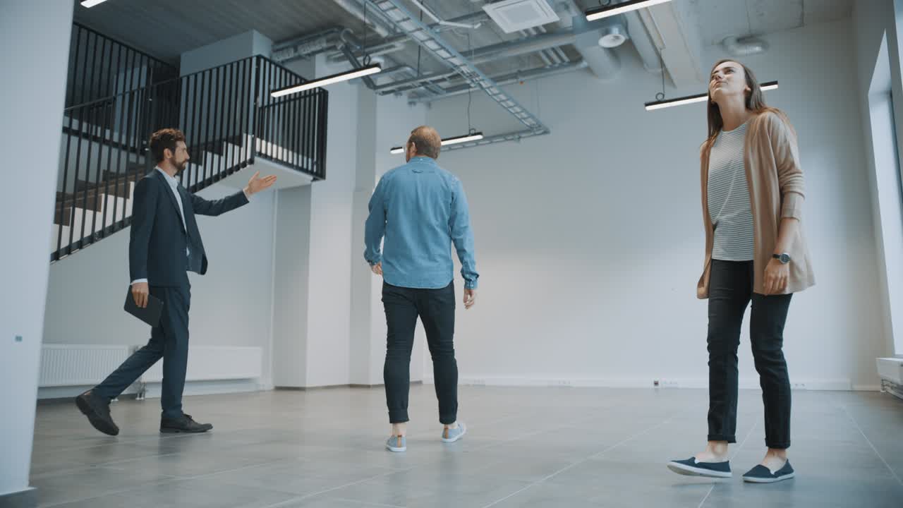 新しい空いたオフィススペースを若い男性と女性ヒップスターに見せている不動産エージェント起業家はタブレットを持ってブローカーに会い購入またはレンタルしたい施設について話し合います - - - -