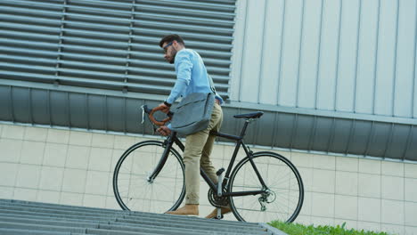 View-from-below-of-young-man-riding-a-bike,-then-carrying-it-down-the-stairs-in-the-city-center