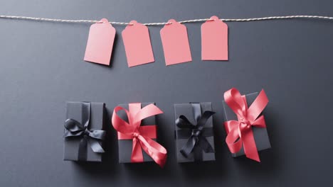 video of gift tags on string, gift boxes with ribbons and copy space on black background