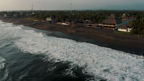 Vista-Aérea-De-Drones-De-Olas-Espumosas-Rompiendo-Sobre-La-Playa-De-Arena-Negra-De-Monterrico,-Guatemala