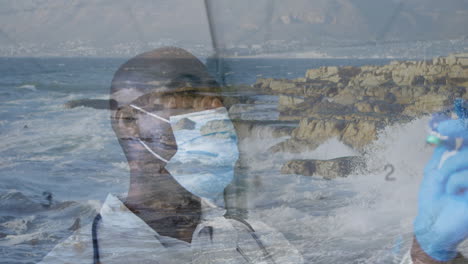 wearing mask, healthcare professional standing by ocean waves and rocky coastline