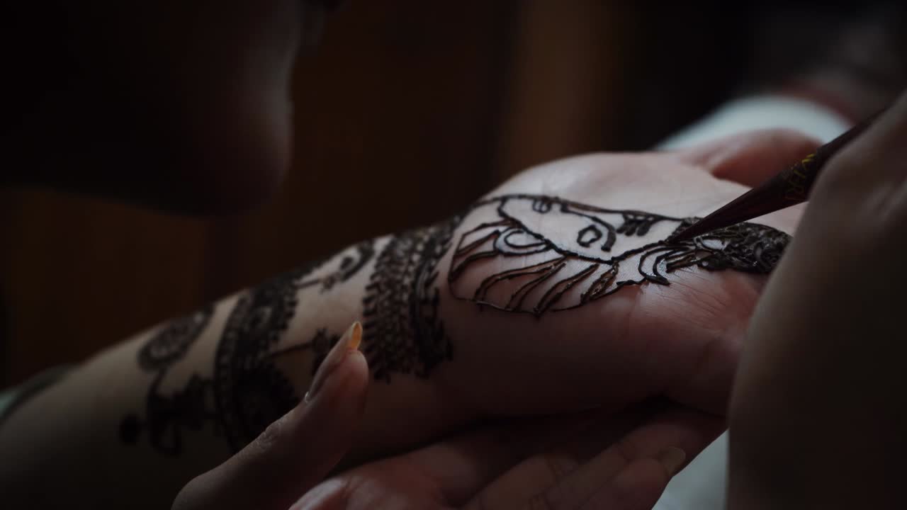 Donna artista di Mehendi che dipinge l'henné sulla mano nella città di Agra, India. - Ripresa dall'alto.