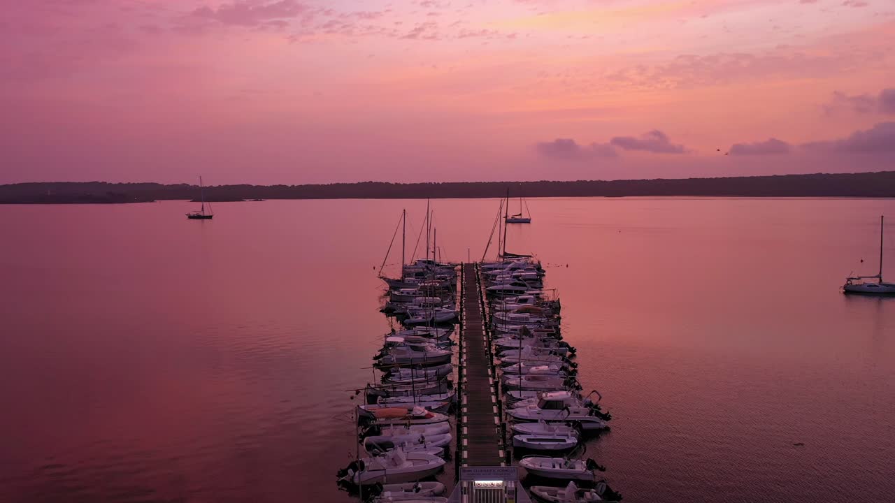 vista aérea de barcos en un muelle con una hermosa puesta de sol, siguiendo una toma amplia