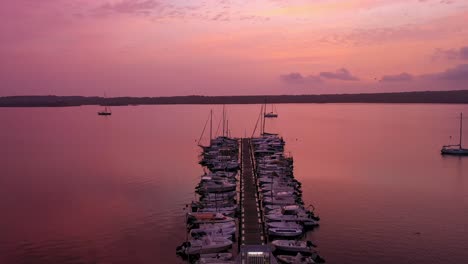 vista aérea de barcos en un muelle con una hermosa puesta de sol, siguiendo una toma amplia