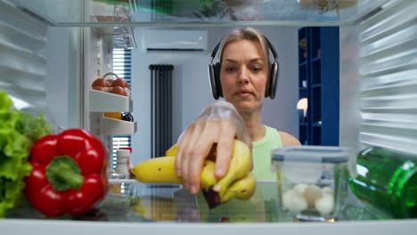 mujer poniendo frutas en un refrigerador