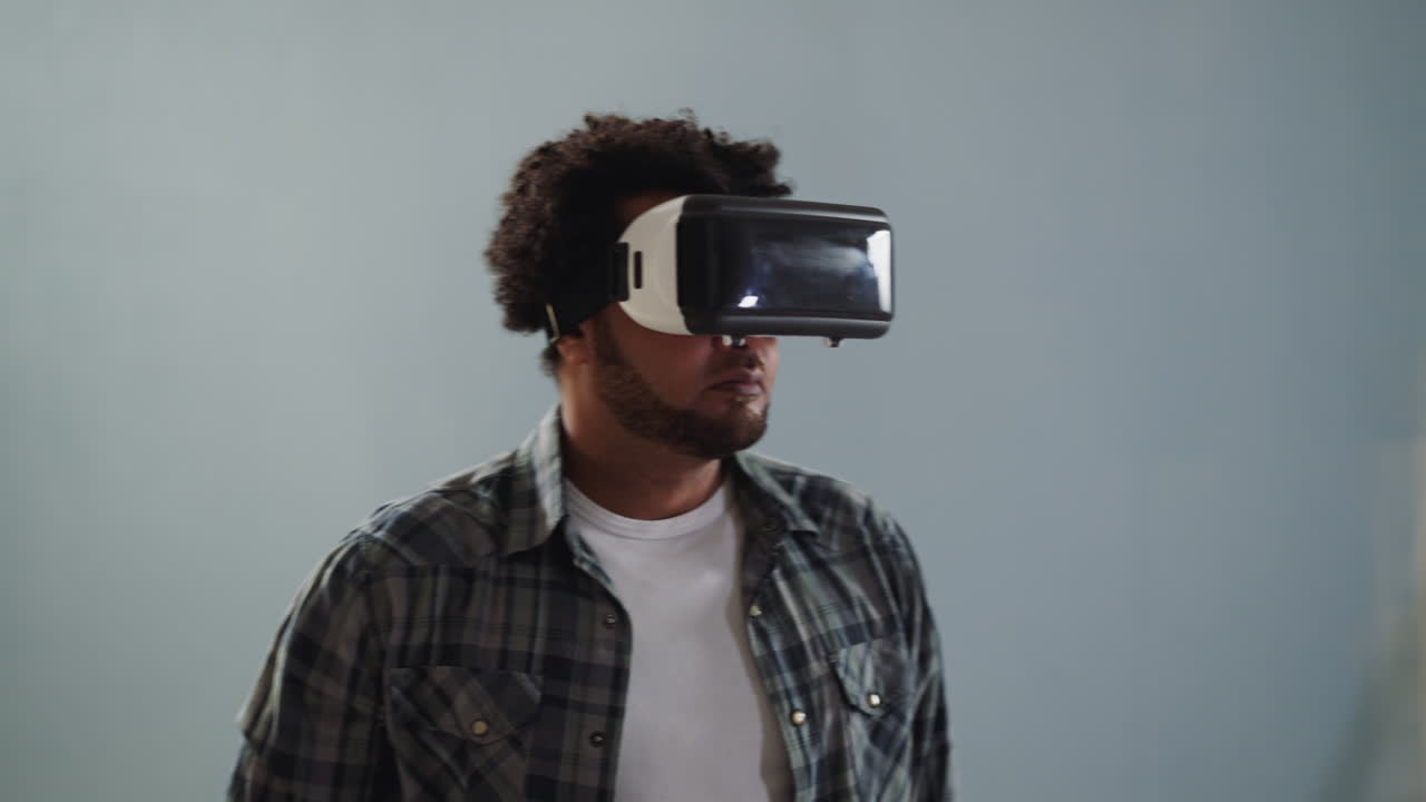 Black guy with VR helmet turns around on grey background