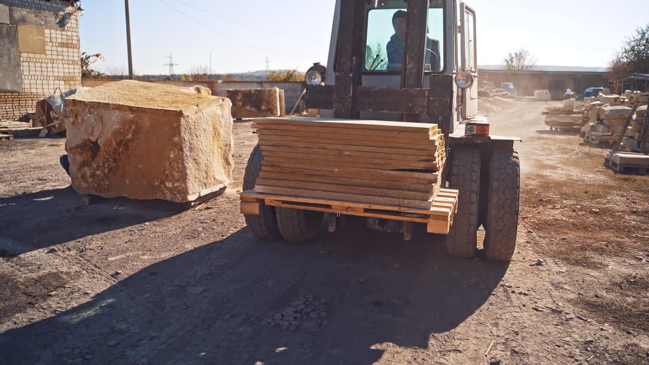 Loader holding marble block. Close up of the forklift forks lifting pallet with marble