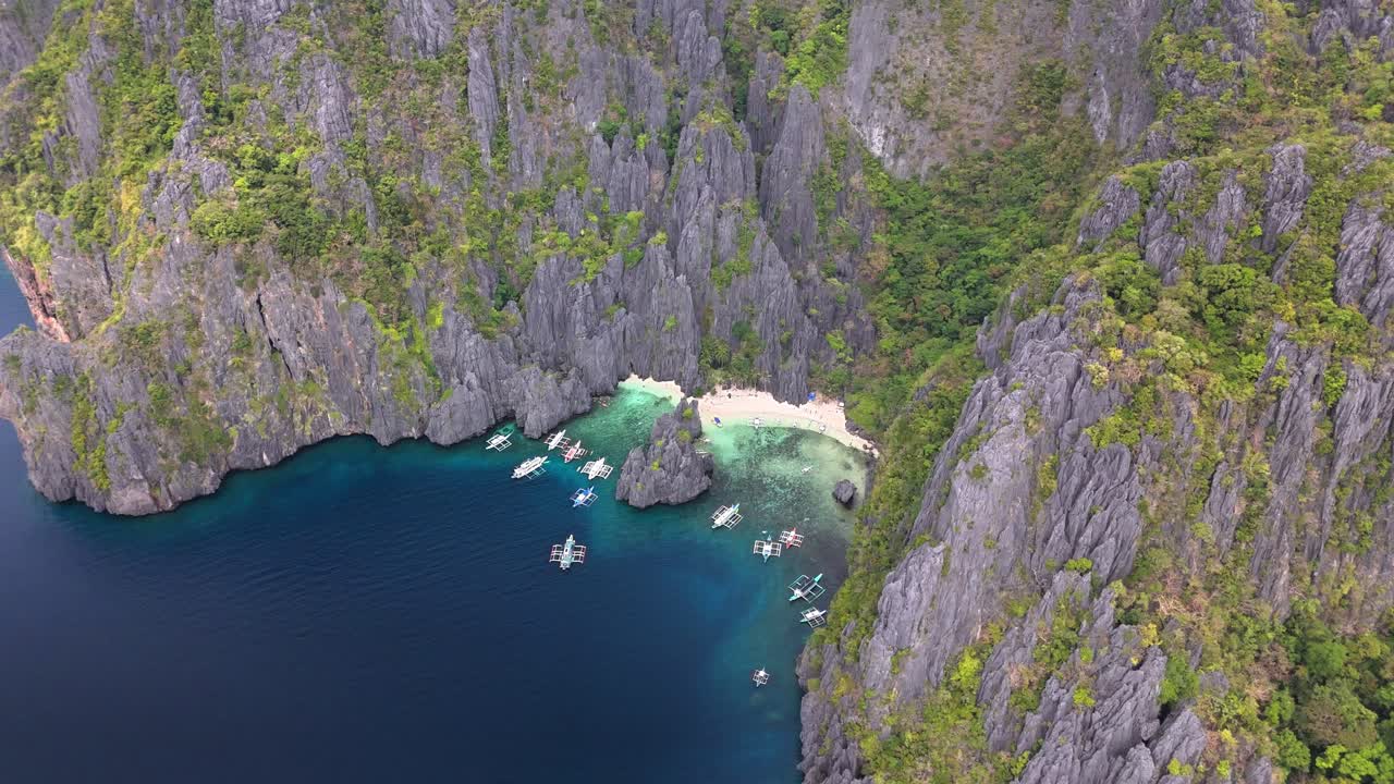 Bird's-eye survey of the beautiful Secret Lagoon and Jiji's Beach with boats, Miniloc Island, Philippines