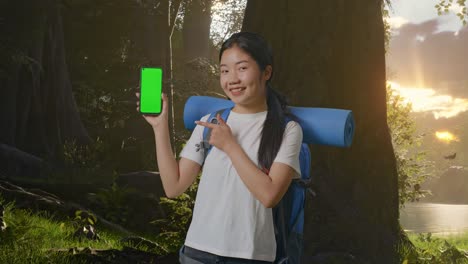 초록색 화면 전화로 숲에서 하이킹하는 여자