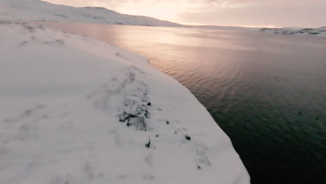 fpv dolly forward above snowy ocean shoreline