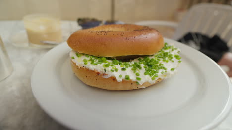 Fresh-bagel-with-cream-cheese-and-chives-on-a-white-plate