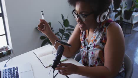 vlogger afroamericana de talla grande con auriculares grabando un video blog usando el micrófono