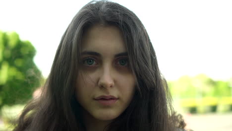 Young-Italian-Woman-with-gorgeous-eyes-at-the-Park-during-bright-sunlight-looking-at-the-camera,-Portrait-shot